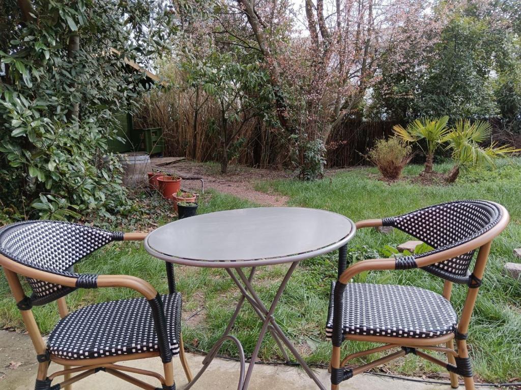 2 sillas y una mesa en un jardín en Au jardin Parisien en Argenteuil