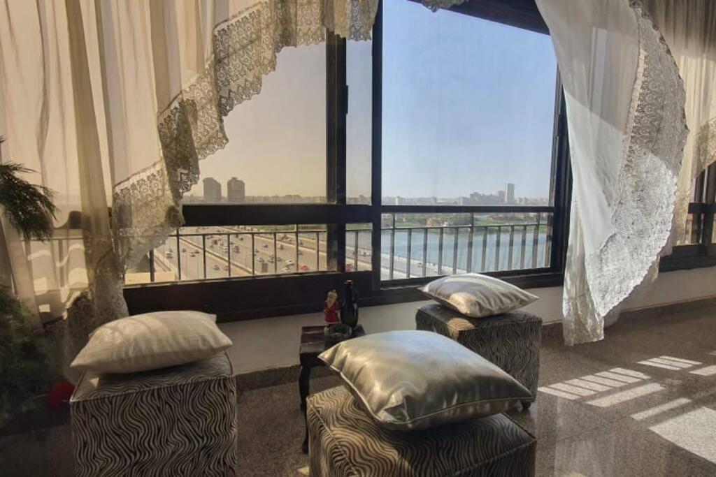 a room with two stools in front of a large window at EGP NILE&PYRAMIDS view Duplex 3BHK- BGhomes in Cairo