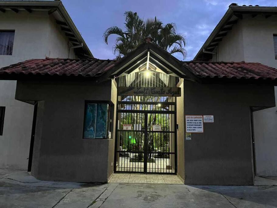ein Tor zu einem Haus mit einer Palme dahinter in der Unterkunft Condomínio Costa Azul in Caraguatatuba