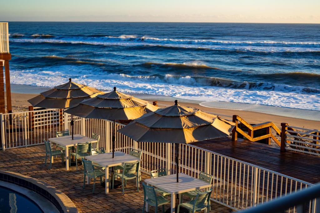 墨爾本海灘的住宿－Melbourne Beach Resort，海滩上带桌子和遮阳伞的甲板