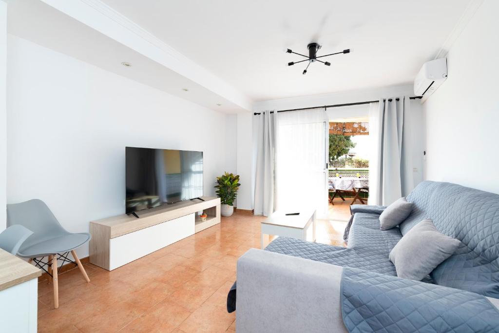 un salon avec un canapé bleu et une télévision dans l'établissement BrisaMar II primera línea de playa & priv parking, à Torre de Benagalbón