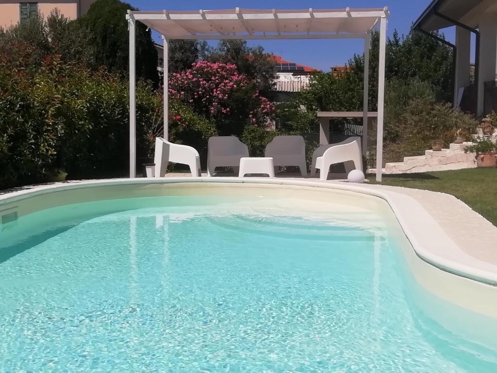 einen Pool mit Stühlen und einem Pavillon in der Unterkunft Alba Marina Rooms in Tollo