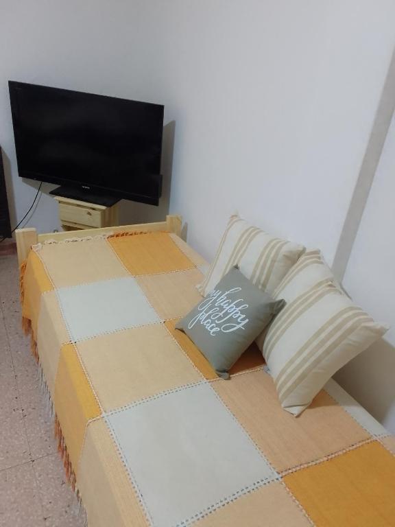 Bett mit Kissen und TV in einem Zimmer in der Unterkunft Alojamiento por dia in Bahía Blanca