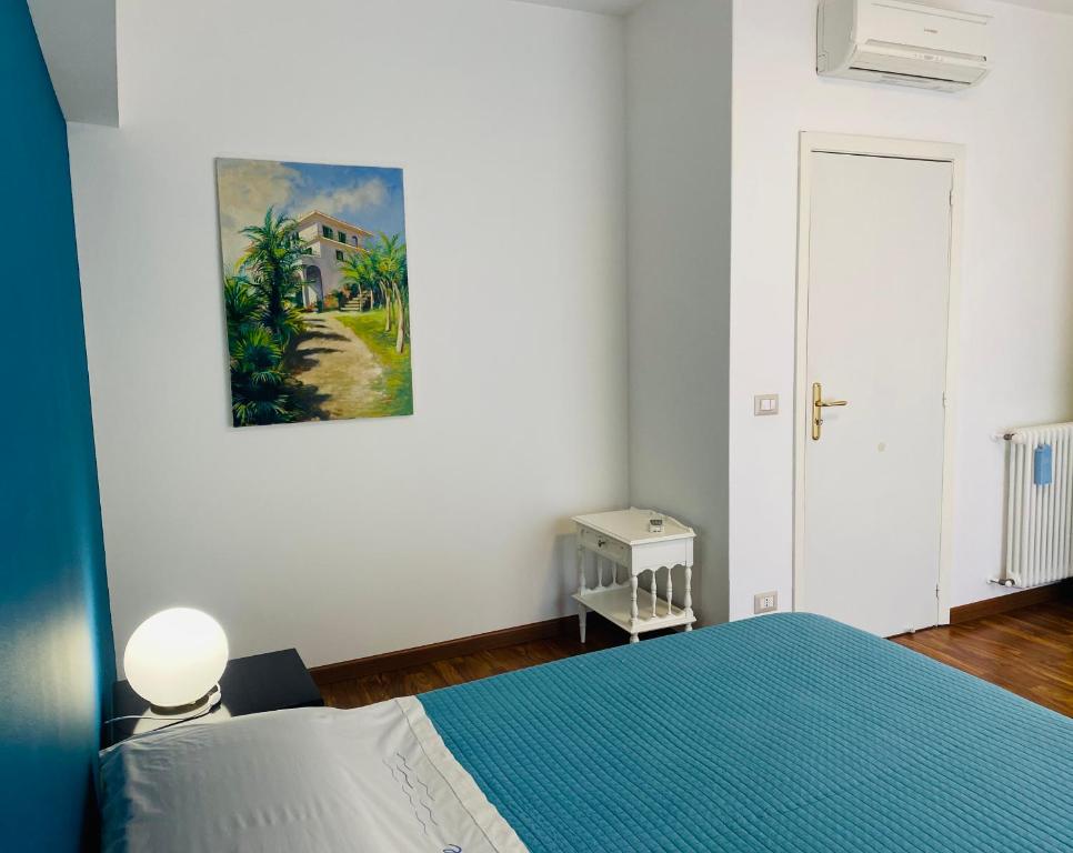 a bedroom with a blue bed and a painting on the wall at Mareluce in Letojanni