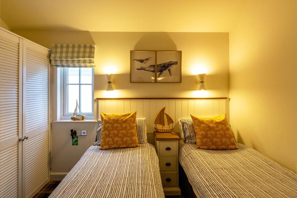 a bedroom with two beds with pillows and a window at Filey Bay Beach House Holiday Home The Bay Filey in Filey