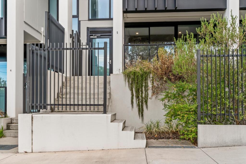 a staircase in front of a building with a fence at StayAU Modern 2BR Townhouse w/ pool in Oakleigh