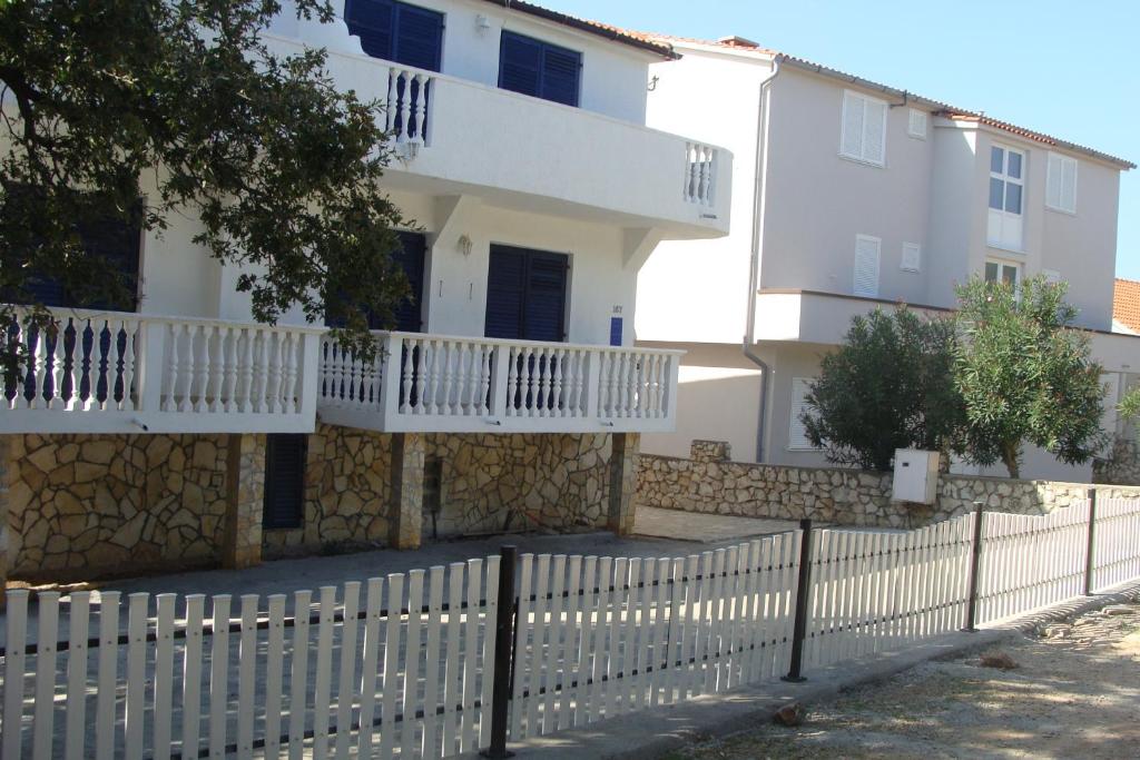 a white house with a fence in front of it at Apartments Sabol Geist in Borovići