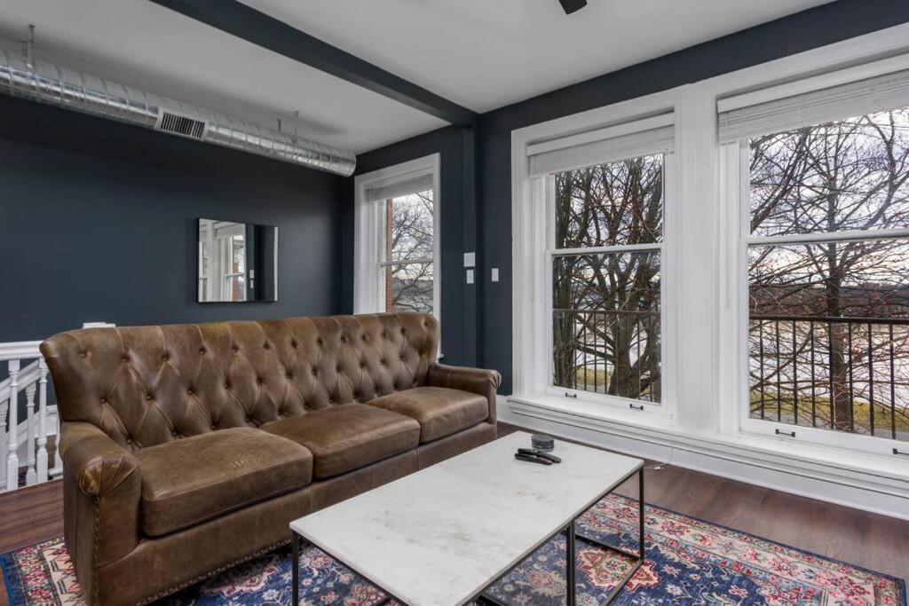 a living room with a couch and two windows at Flats on Front - Riverfront Gem Fast Wi-Fi 3F in Harrisburg