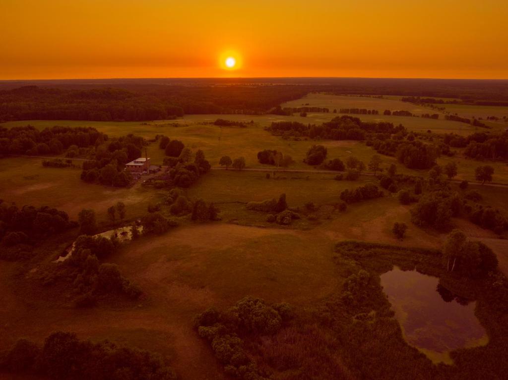 eine Luftansicht eines Feldes mit Sonnenuntergang im Hintergrund in der Unterkunft CAMP Agroturystyka Gorzelnia Gwieździn in Gwieździn