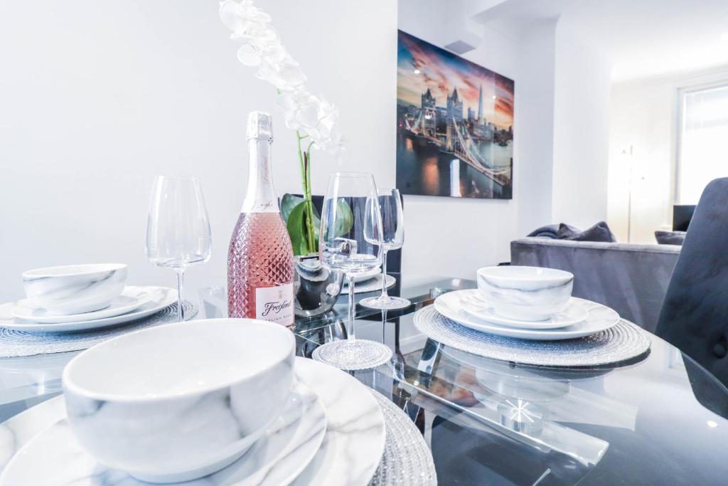 a dining room table with white dishes and a bottle of wine at Great 3 Bed Refurbished House in Colchester