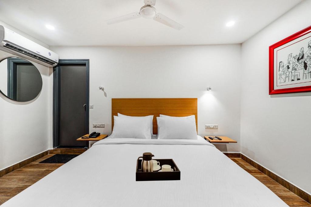 a bedroom with a large white bed with a wooden headboard at Townhouse De Alphabet Tirupati in Tirupati