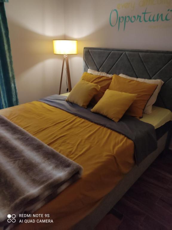 a bedroom with a bed with yellow sheets and a lamp at Kuca za odmor Milica in Vrnjačka Banja