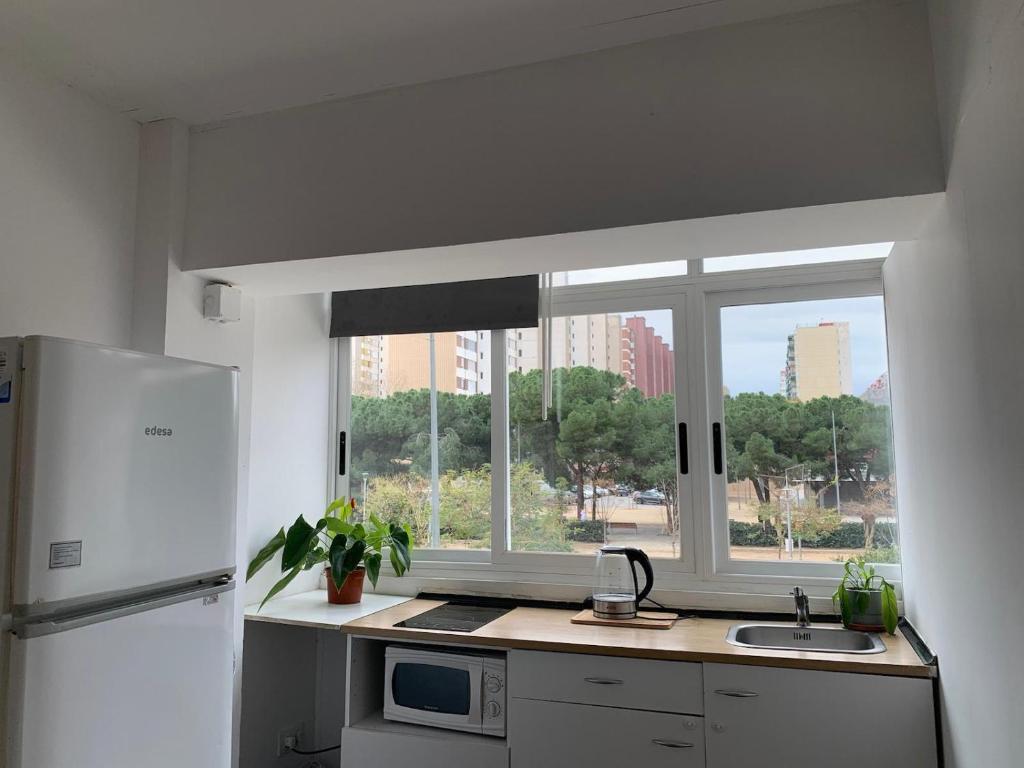 cocina con nevera blanca y ventana en SLEEPER LLUM, en Las Corts