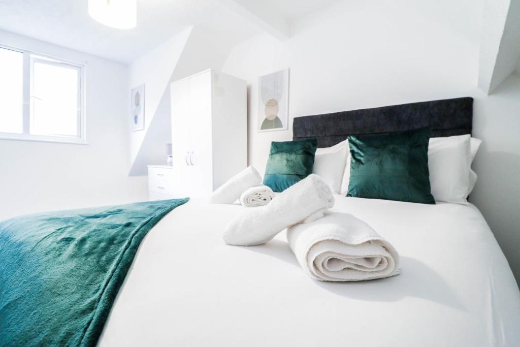 a bedroom with a white bed with towels on it at Affordable-Contractor 5 Bed House with Driveway! in Luton