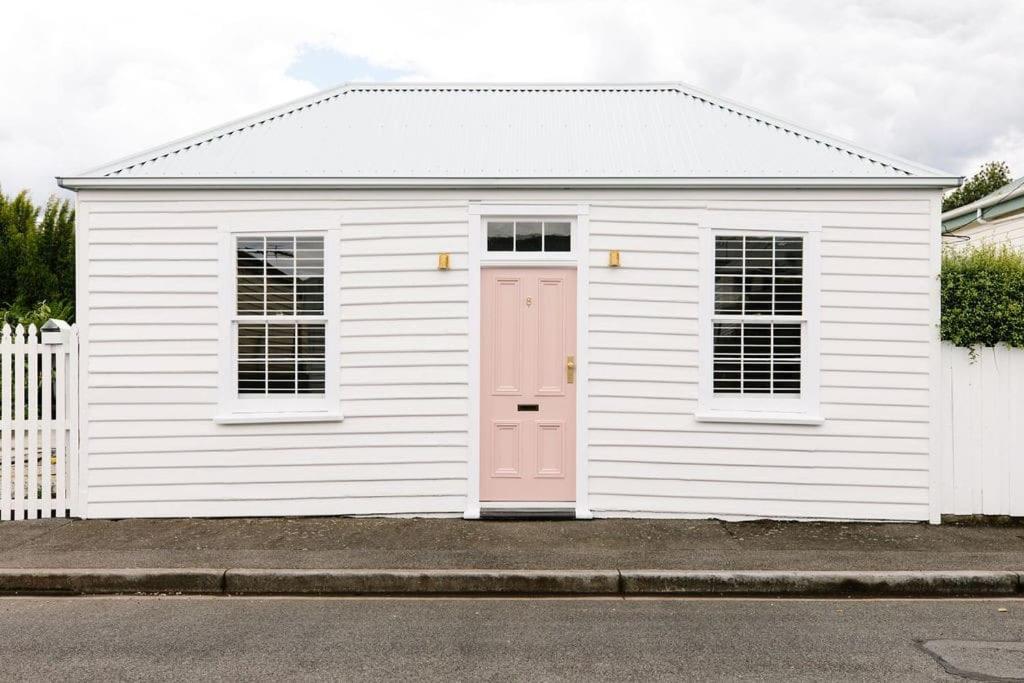um pequeno edifício branco com uma porta rosa em Good Soul Cottage em Invermay