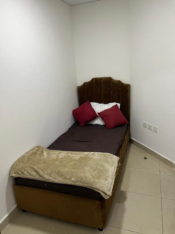 Una cama pequeña con dos almohadas rojas. en F22R4 Small room attach bath at beach, en Ajman