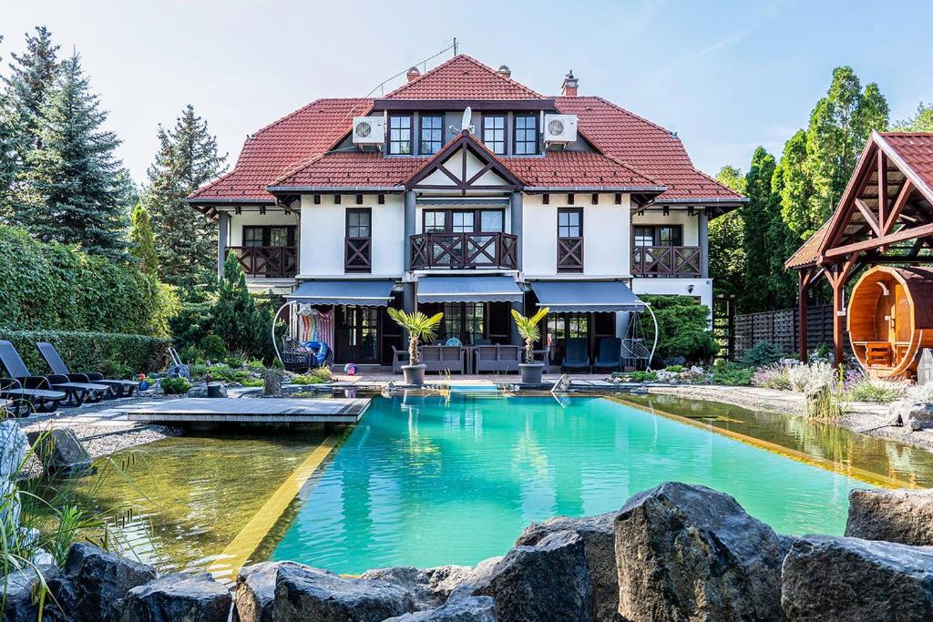 a house with a large swimming pool in front of it at Castle Residence Balaton in Balatonföldvár