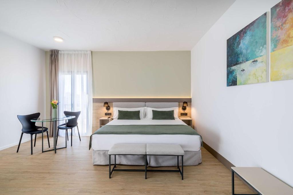 a bedroom with a bed and a table and chairs at Occidental Puerto Banús in Marbella