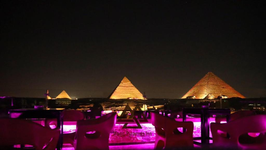 a view of the pyramids at night with pink lights at MAGIC Pyramids Hotel in Cairo