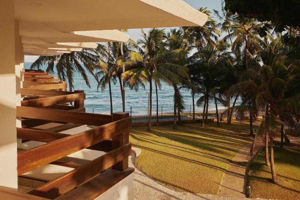 uma vista para uma praia com palmeiras e para o oceano em Flat Amplo e Confortável à Beira Mar em Jatiúca! em Maceió