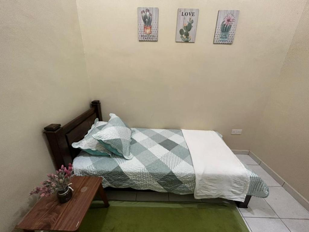a bedroom with a bed and a wooden table at HomestayMuslim Safiyya in Sungai Petani