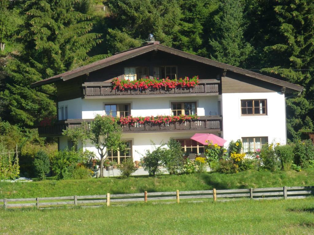 a white house with red flowers on a balcony at Haus Andrea Unterberger in Flachau