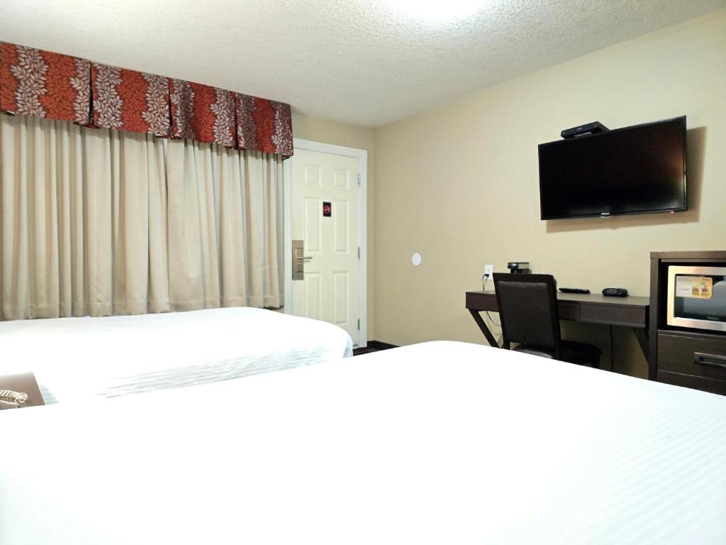 Habitación de hotel con 2 camas, escritorio y TV. en Royal Lodge en Edmonton