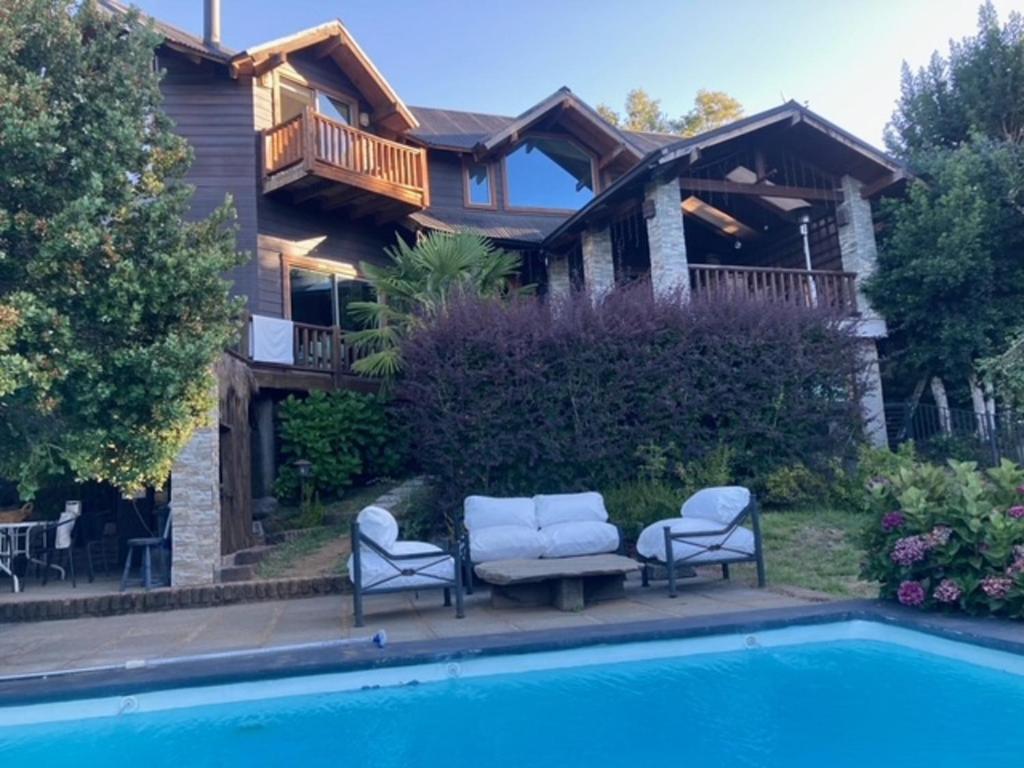 a house with a swimming pool in front of a house at Das Gästehaus, Pucón, Casa de Huéspedes in Pucón