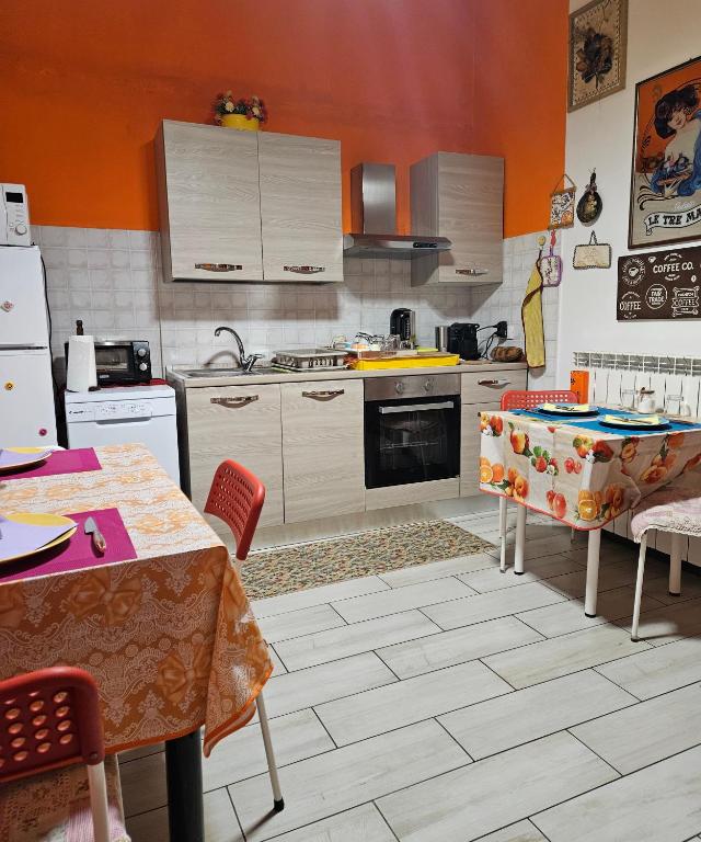 kuchnia z pomarańczowymi ścianami oraz białymi urządzeniami i stołami w obiekcie B&B Villa Emilia Milano w Mediolanie