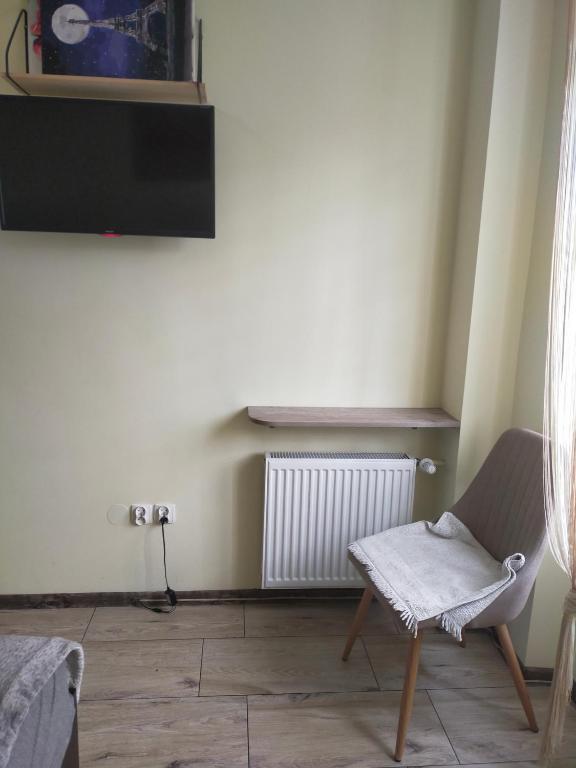 a room with a chair and a tv on a wall at Like People in Krakow