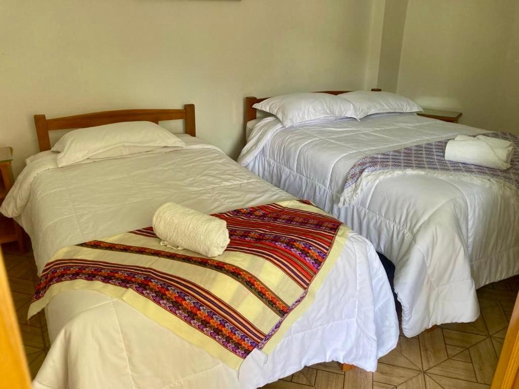 Dos camas con sábanas blancas y una manta. en El Oasis de Dorita en Caraz