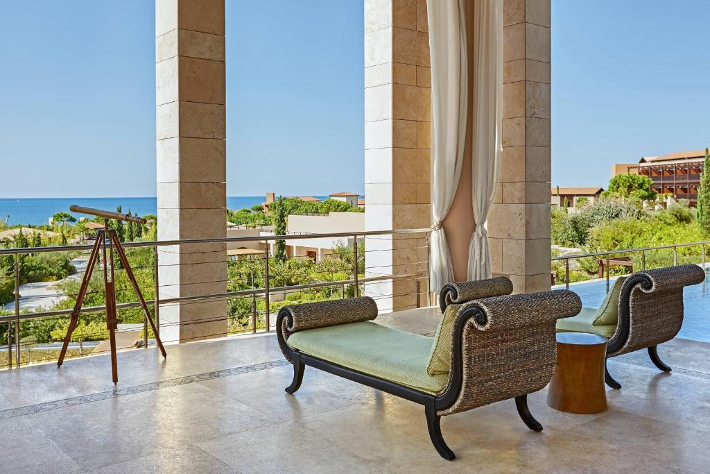 a balcony with chairs and a table and a view of the ocean at The Romanos, a Luxury Collection Resort, Costa Navarino in Romanu