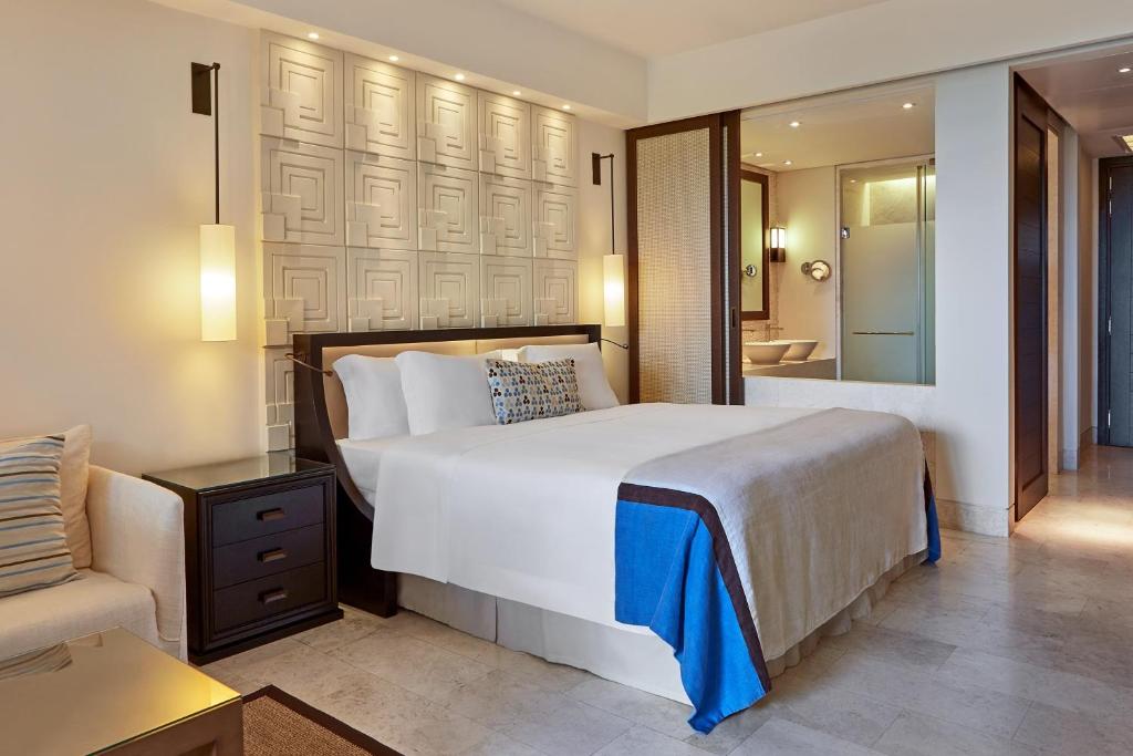 a bedroom with a large white bed and a couch at The Romanos, a Luxury Collection Resort, Costa Navarino in Romanu