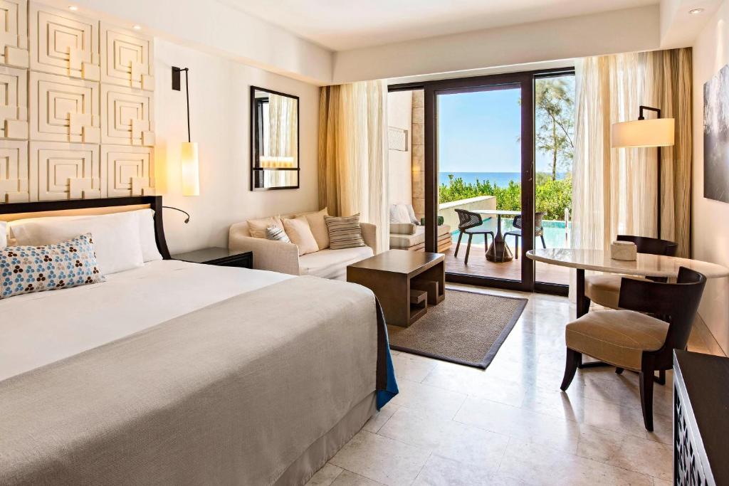 a hotel room with a bed and a living room at The Romanos, a Luxury Collection Resort, Costa Navarino in Romanu