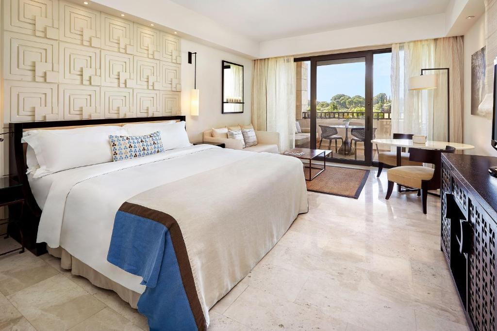 a bedroom with a large bed and a living room at The Romanos, a Luxury Collection Resort, Costa Navarino in Romanu