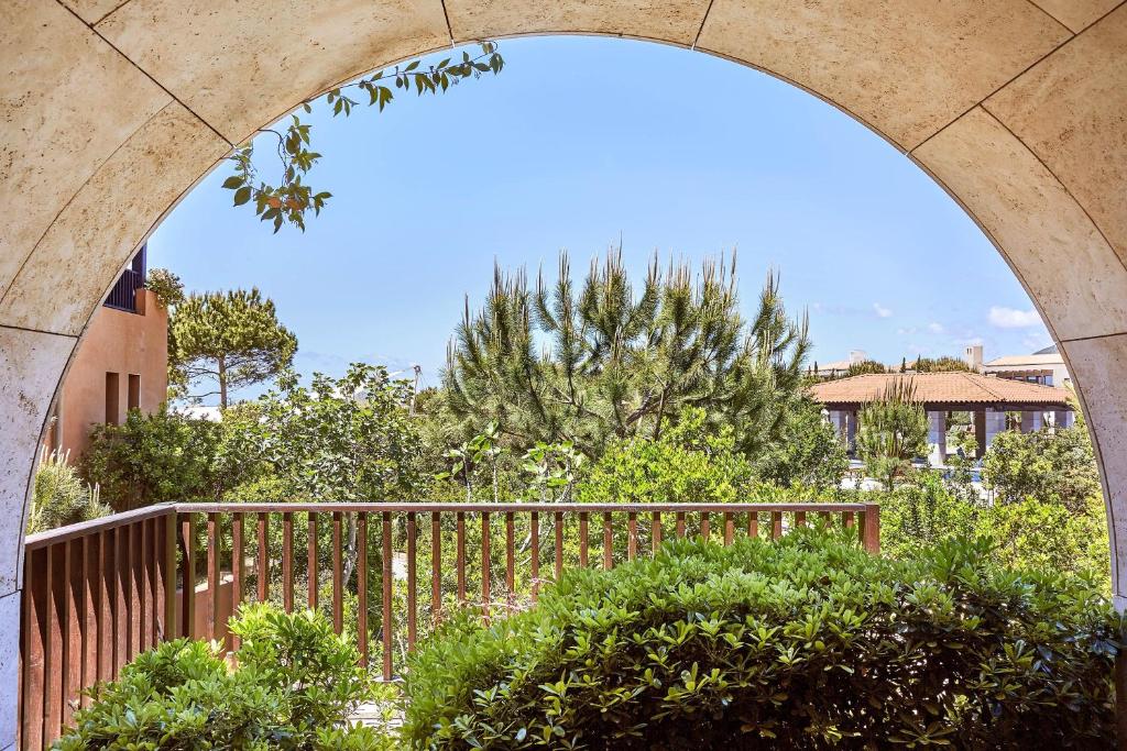 an archway over a fence with trees and bushes at The Romanos, a Luxury Collection Resort, Costa Navarino in Romanu
