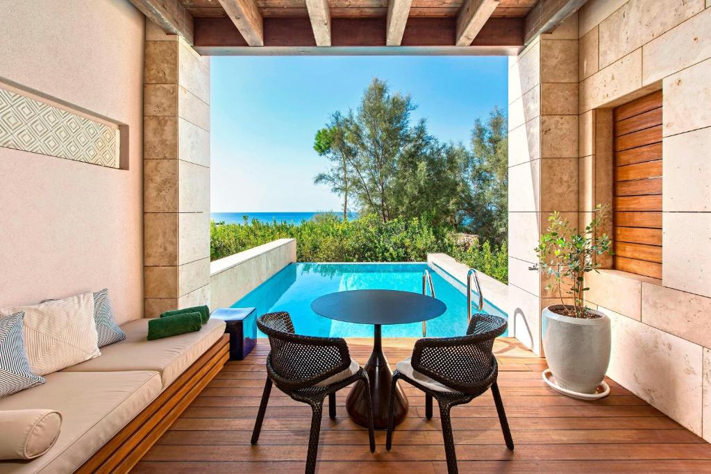 a patio with a table and chairs and a pool at The Romanos, a Luxury Collection Resort, Costa Navarino in Romanu