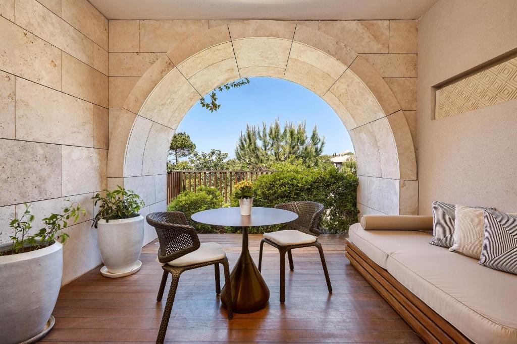 a patio with a couch and a table and chairs at The Romanos, a Luxury Collection Resort, Costa Navarino in Romanu