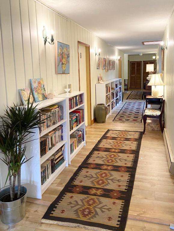 a hallway with a library with bookshelves and a rug at Wisteria Guest House in Ganges