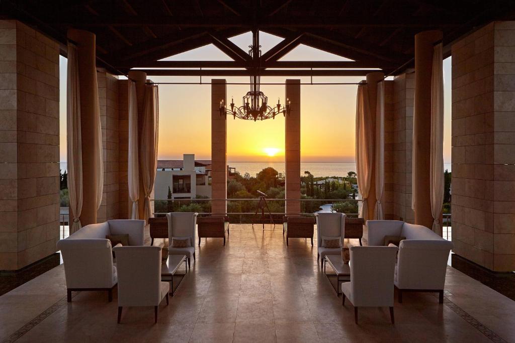 a room with chairs and a chandelier and the sunset at The Romanos, a Luxury Collection Resort, Costa Navarino in Romanu