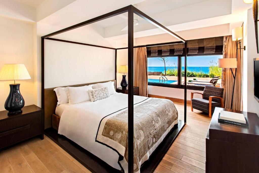 a bedroom with a bed and a view of the ocean at The Romanos, a Luxury Collection Resort, Costa Navarino in Romanu