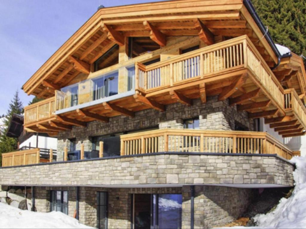 a log home with a large deck on top at Haus am Hang in Saalbach-Hinterglemm
