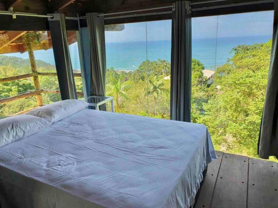 a bed in a room with a view of the ocean at Casa Azul da Cor do Mar in Paraty
