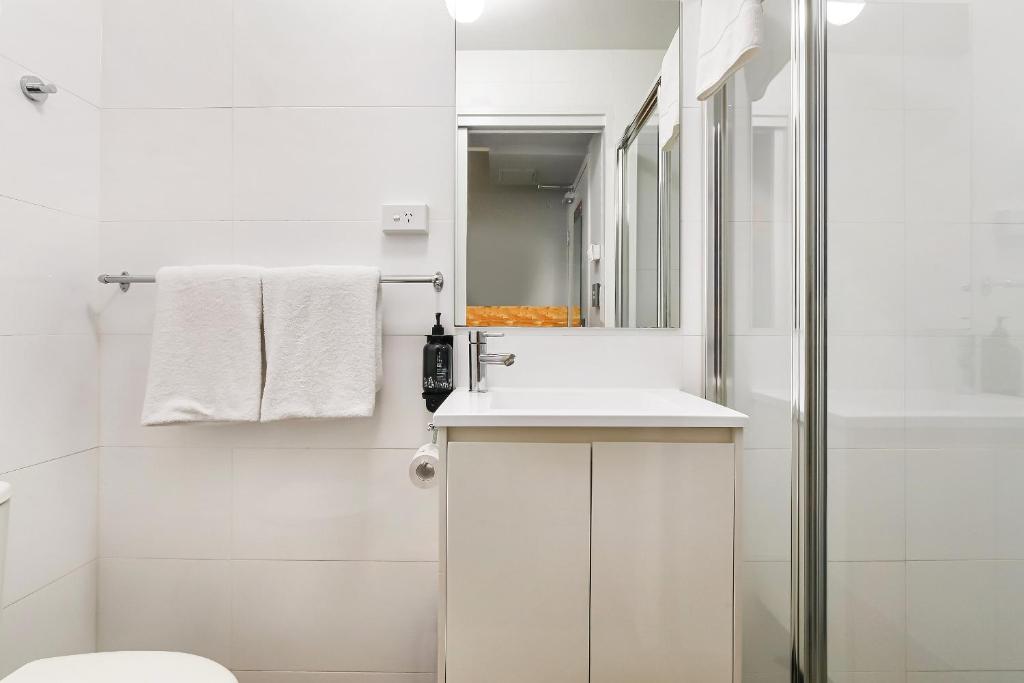 a white bathroom with a sink and a shower at The Urban Newtown in Sydney