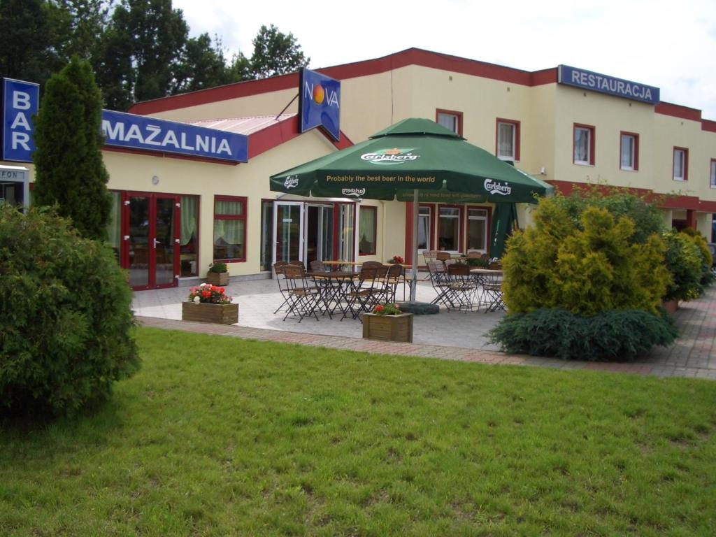 ein Gebäude mit Tischen und einem Sonnenschirm davor in der Unterkunft Restauracja - Hotel Nova in Skępe