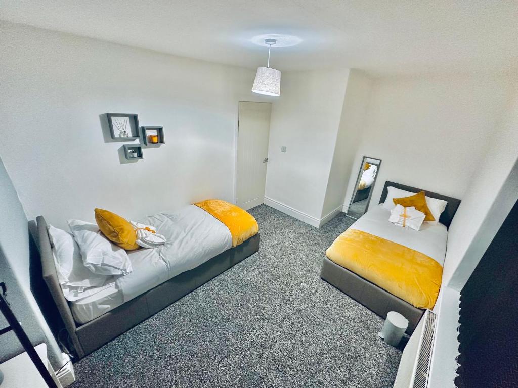 um quarto com 2 camas com lençóis amarelos em *Newcastle City* Modern 2 Bedroom House em Newcastle upon Tyne