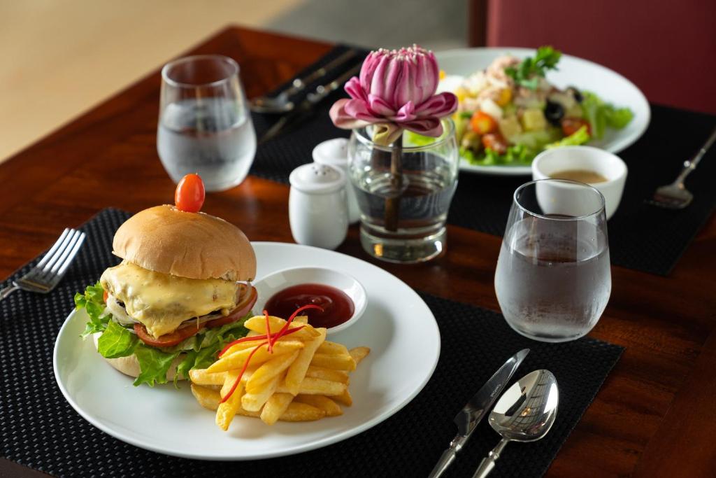 a table with two plates of food with a sandwich and fries at Sala Siem Reap Hotel in Siem Reap
