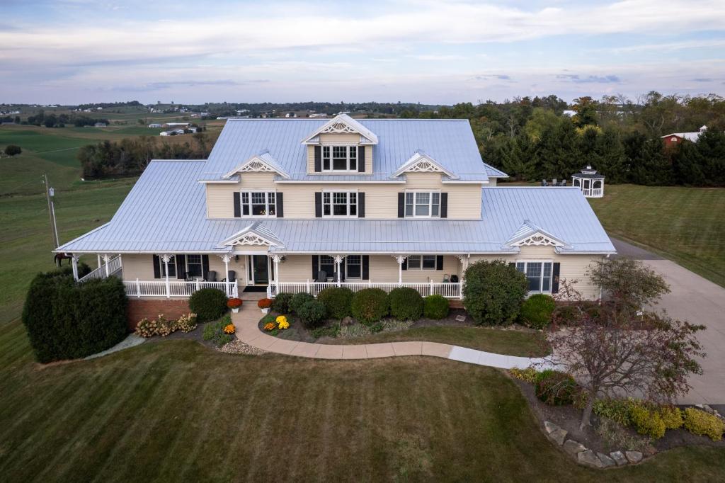 une vue aérienne sur une maison blanche avec un toit bleu dans l'établissement Hillside Villa Ohio, à Millersburg