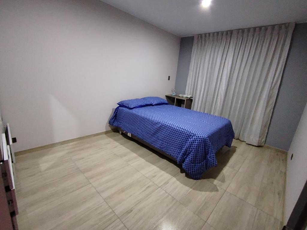 1 dormitorio con 1 cama con manta azul en Departamento moderno en el centro de la ciudad, en Ilo