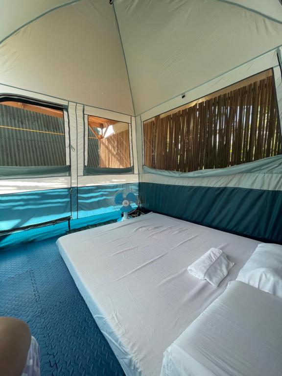 a large bed in a tent with two windows at Russell Place Tent in Port Barton